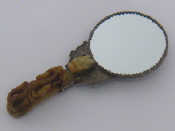 Appraisal: A Chinese hand mirror mounted in white metal embossed with