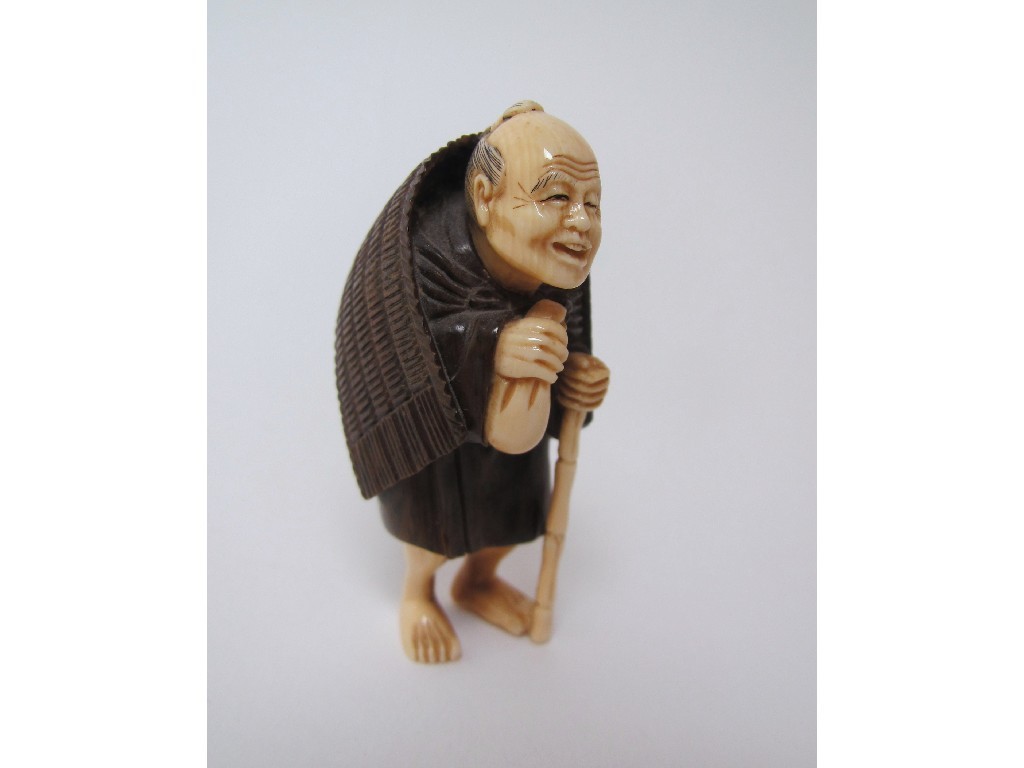 Appraisal: A Japanese ivory and hardwood netsuke of a traveller standing