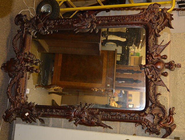 Appraisal: A contemporary carved stained wood wall mirrorwith trophy mounts in