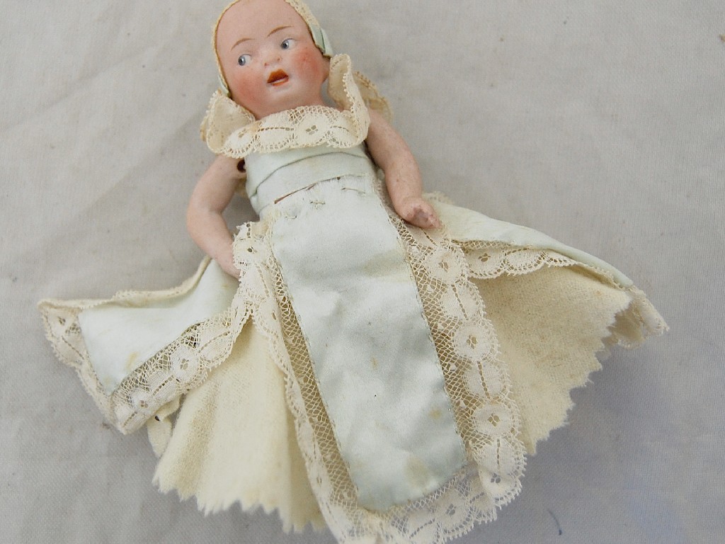 Appraisal: A miniature bisque baby doll with jointed limbs in silk