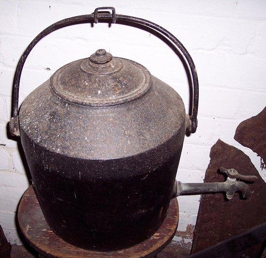 Appraisal: An iron tea urn with swing handle marked Clark Co