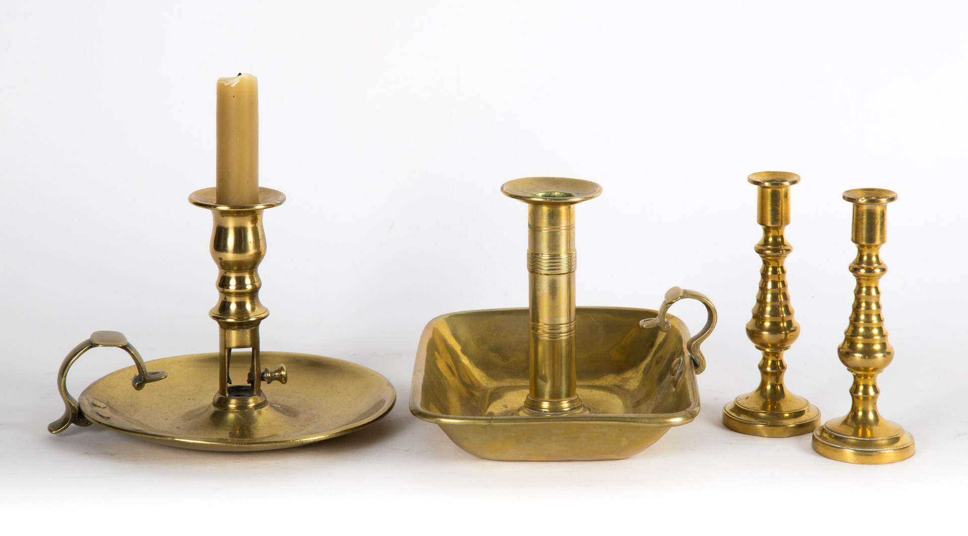 Appraisal: Four assorted antique brass candlesticks th century including chamberstick square