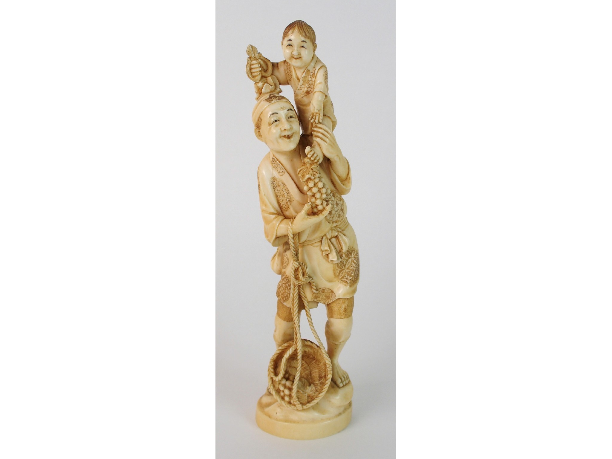 Appraisal: A Japanese ivory okimono of a mangathering grapes with a