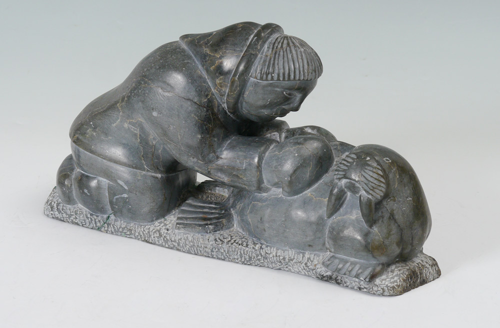 Appraisal: INUIT STONE CARVING OF MAN SKINNING A WALRUS Base with