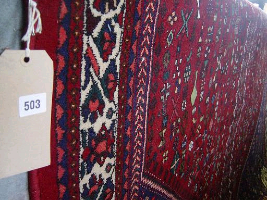 Appraisal: A red ground wool carpet with stylised animal and floral