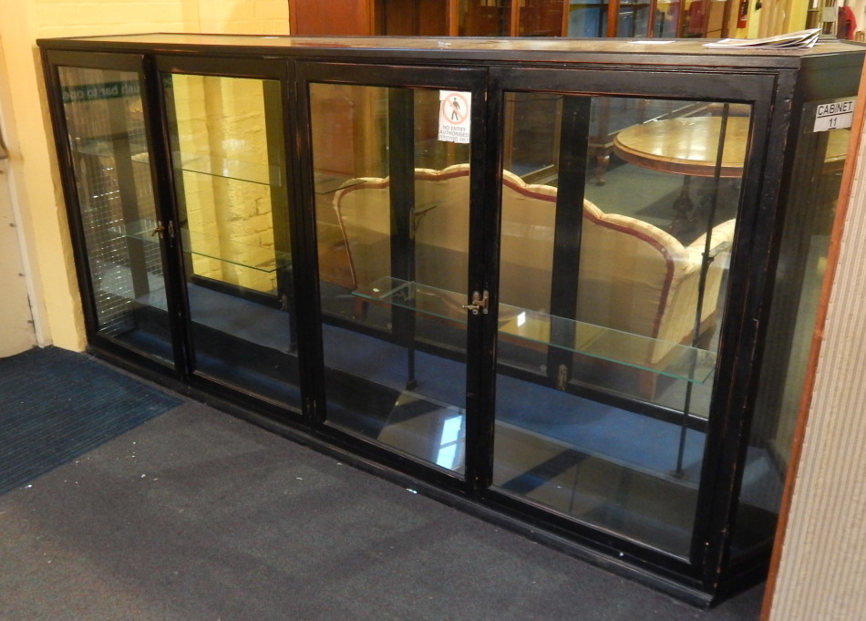 Appraisal: An early thC ebonised shop display cabinet with two pairs