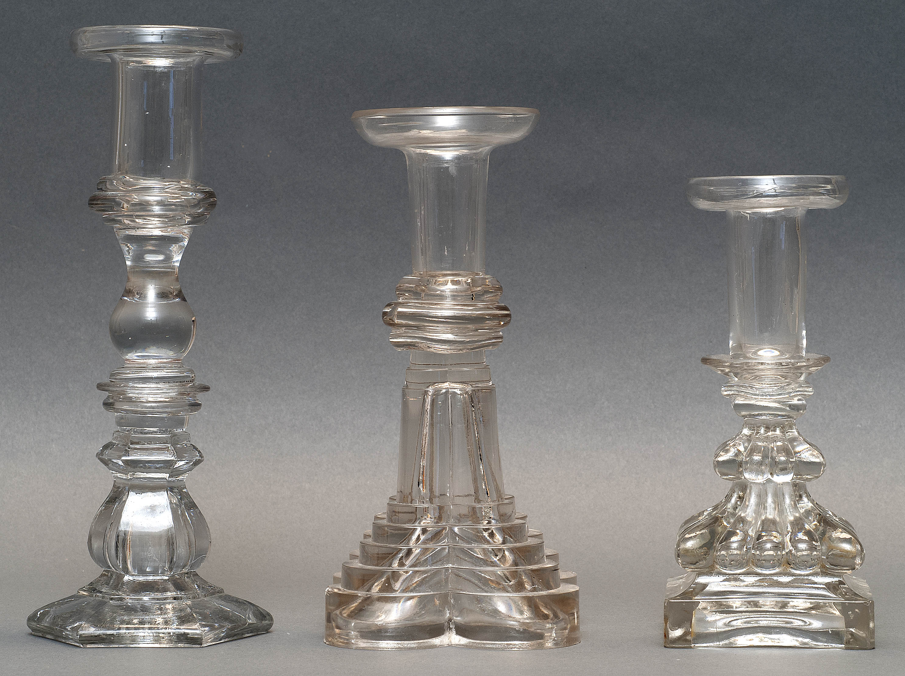 Appraisal: THREE SANDWICH GLASS COMPANY CLEAR GLASS CANDLESTICKS Second Quarter of