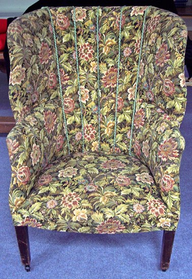 Appraisal: An upholstered wingback armchair with fluted back on square taper