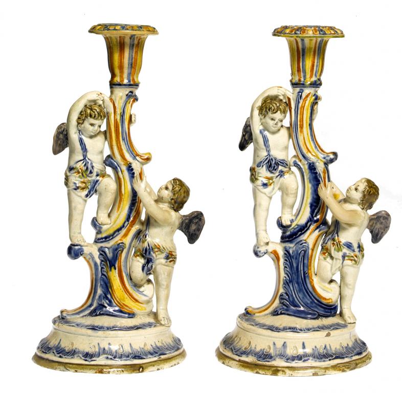 Appraisal: TWO PEARLWARE CANDLESTICKS with putti climbing a scrolling tree trunk