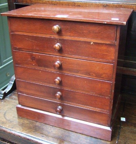 Appraisal: A stained pine collectors chest of six drawers resting on