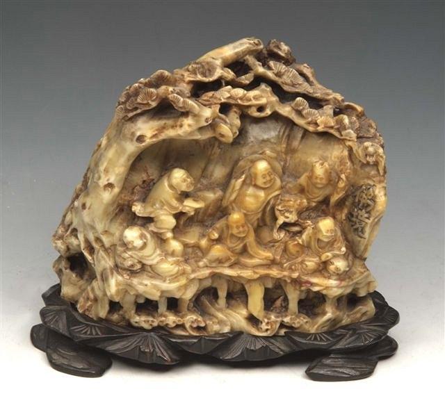 Appraisal: A CHINESE CARVED SOAP STONE GROUP of Immortals seated on