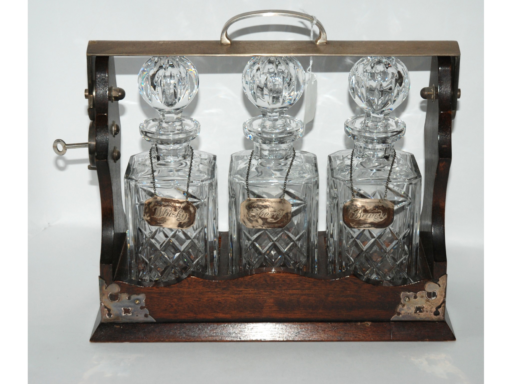 Appraisal: An oak cased and white-metal mounted three bottle Tantalus with