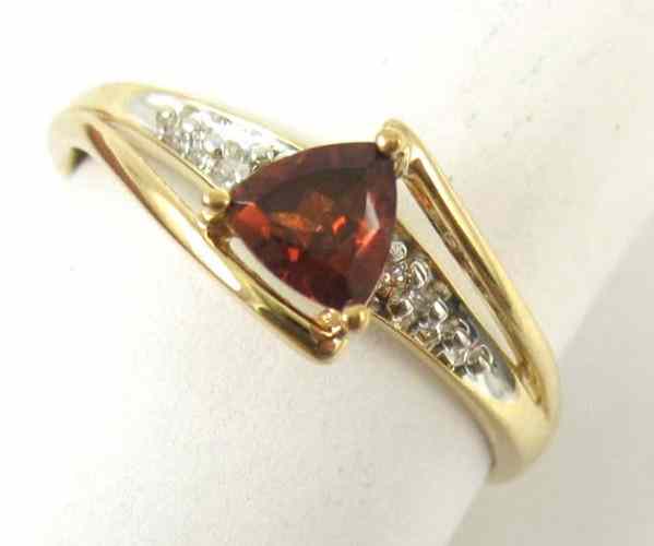 Appraisal: GARNET AND FOURTEEN KARAT GOLD RING set with a trillion-cut