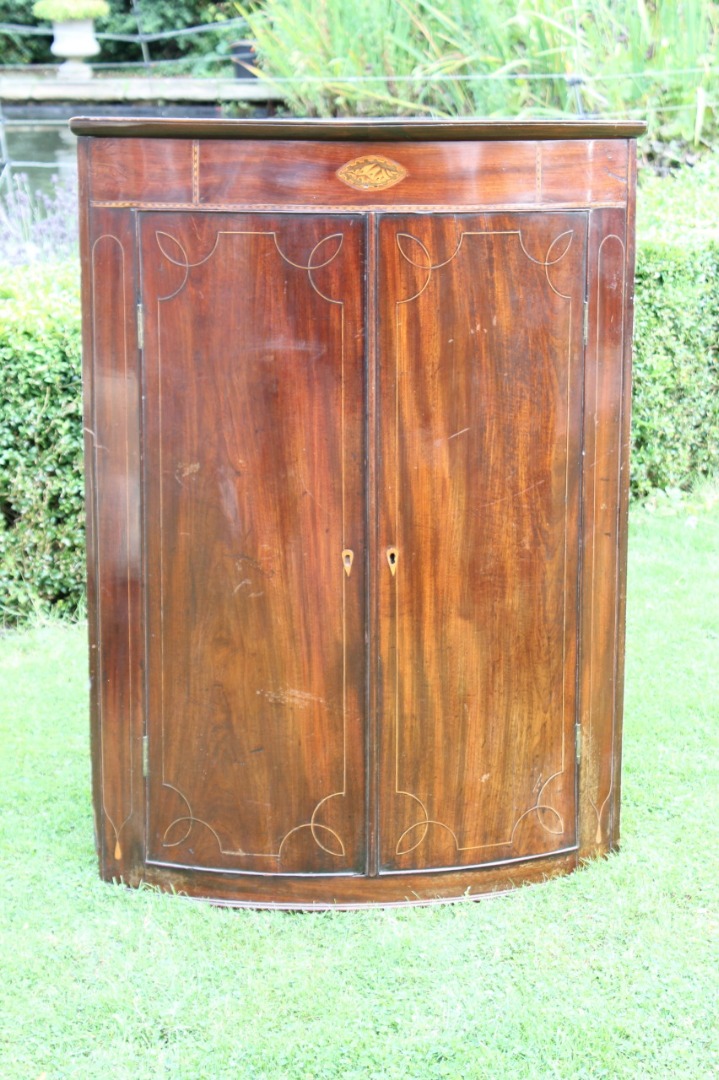 Appraisal: A George III mahogany bowfront corner cupboard with oval shell