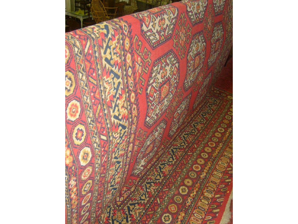 Appraisal: A red ground wool carpet with repeating gul decoration in