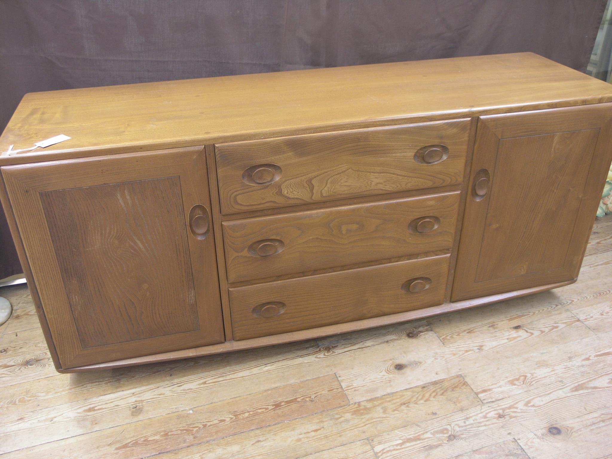 Appraisal: An Ercol golden elm sideboard three central drawers and a