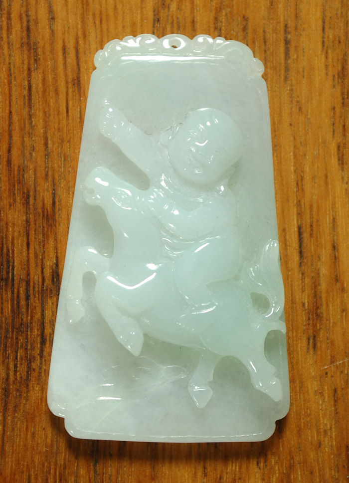 Appraisal: LIGHT GREEN CARVED JADEITE PENDANT featuring a centralized boy on