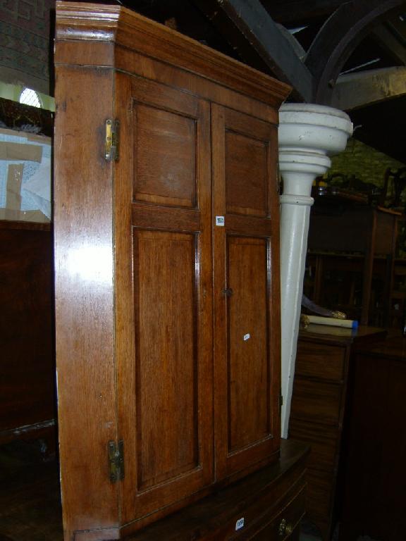 Appraisal: A Georgian oak corner cupboard enclosed by two doors with