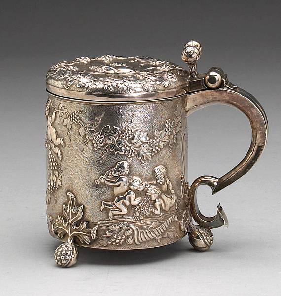 Appraisal: The cylindrical tankard with pomegranate feet and thumbpiece later chased