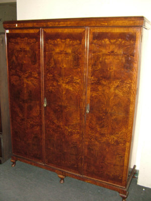 Appraisal: A walnut triple wardrobe the moulded cornice above three doors