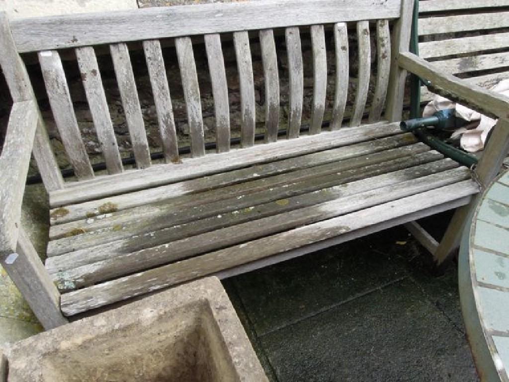 Appraisal: A weathered hardwood garden bench with slatted seat and curved