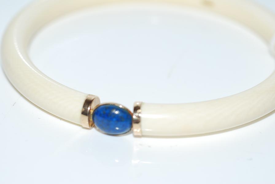 Appraisal: AN IVORY BANGLE WITH LAPIS LAZULI CUT EN CABOCHON AND