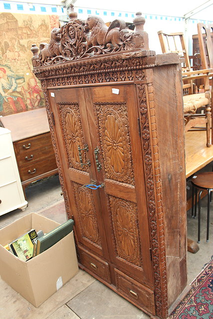 Appraisal: An Indian hardwood cupboard with pierced carved crest two doors