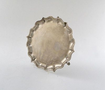 Appraisal: An Edwardian silver waiter of circular form moulded scroll border