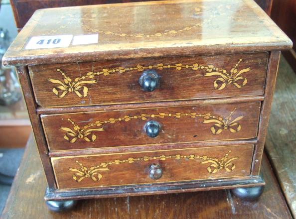 Appraisal: A satinwood banded miniature chest of three long drawers raised