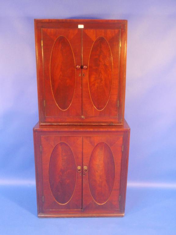 Appraisal: A Georgian mahogany cupboard of two parts each having oval