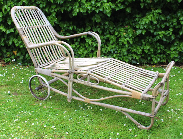 Appraisal: AN ANTIQUE WICKER LOUNGER CHAIR with spoked wheels cm in