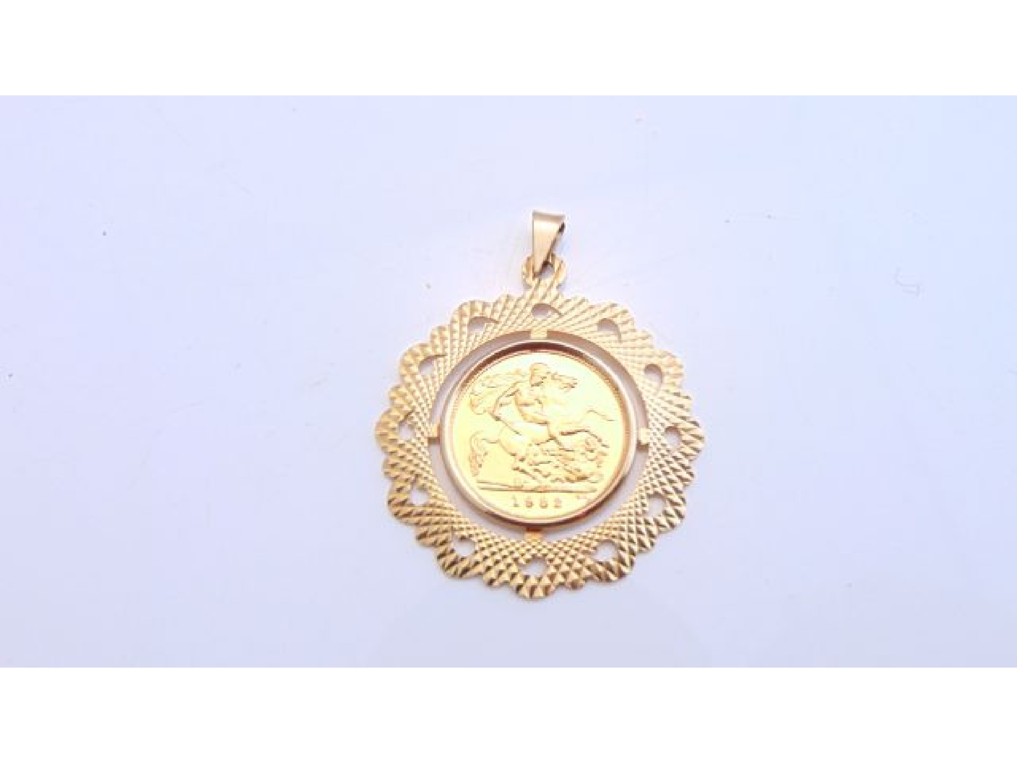 Appraisal: A half sovereign pendant the ct gold border with engine-turned