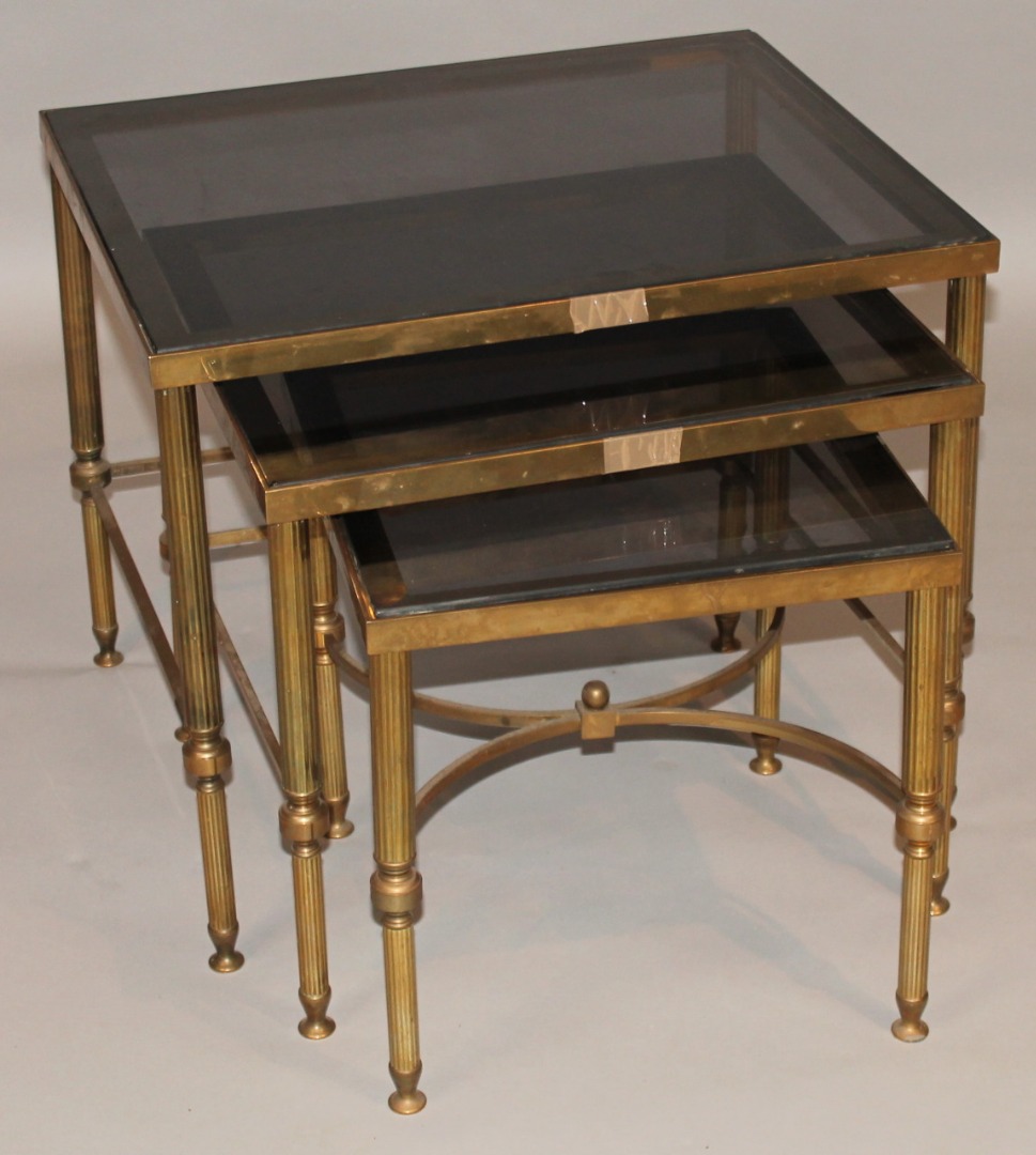 Appraisal: A nest of three brass framed tables with smoky glass