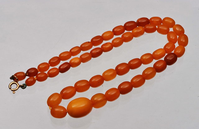 Appraisal: A GRADUATED AMBER BEAD NECKLACE with oval beads long largest