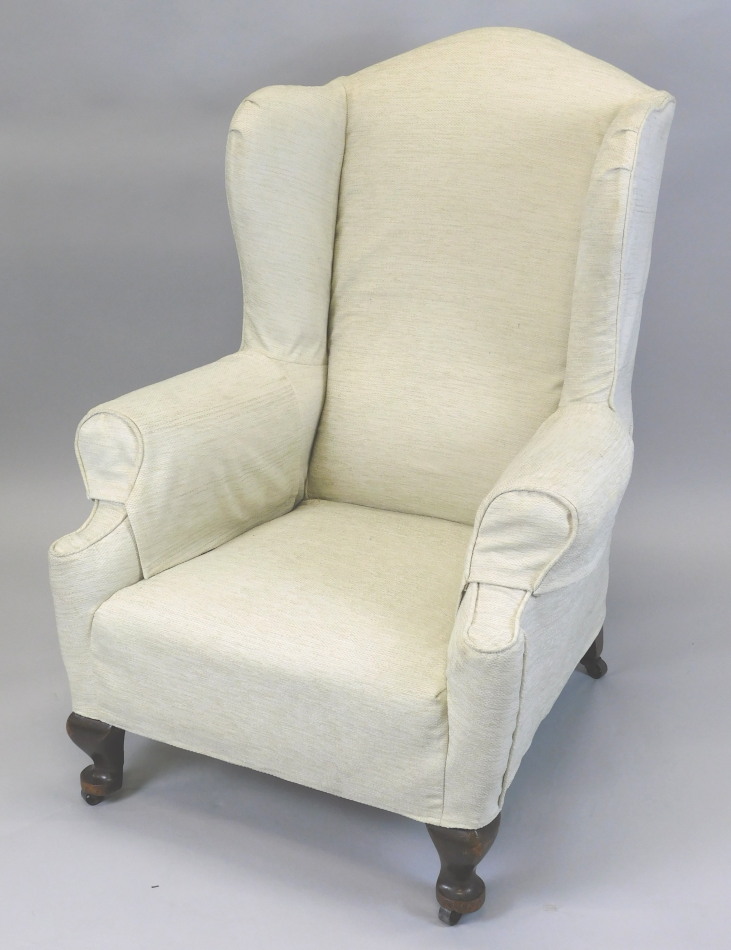 Appraisal: An early thC wingback chair upholstered in cream fabric on