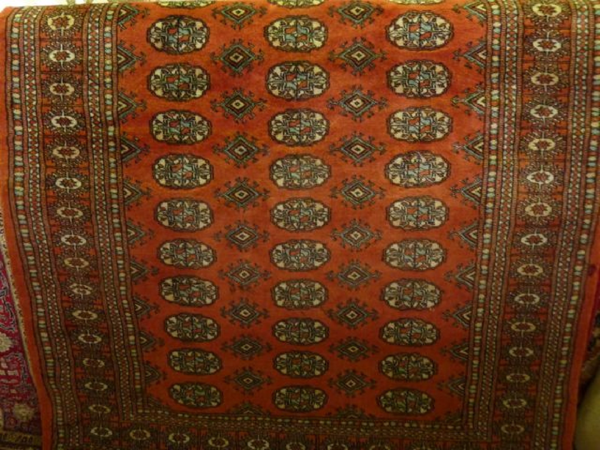 Appraisal: An Afghan wool carpet with pale red field multi-medallion centre