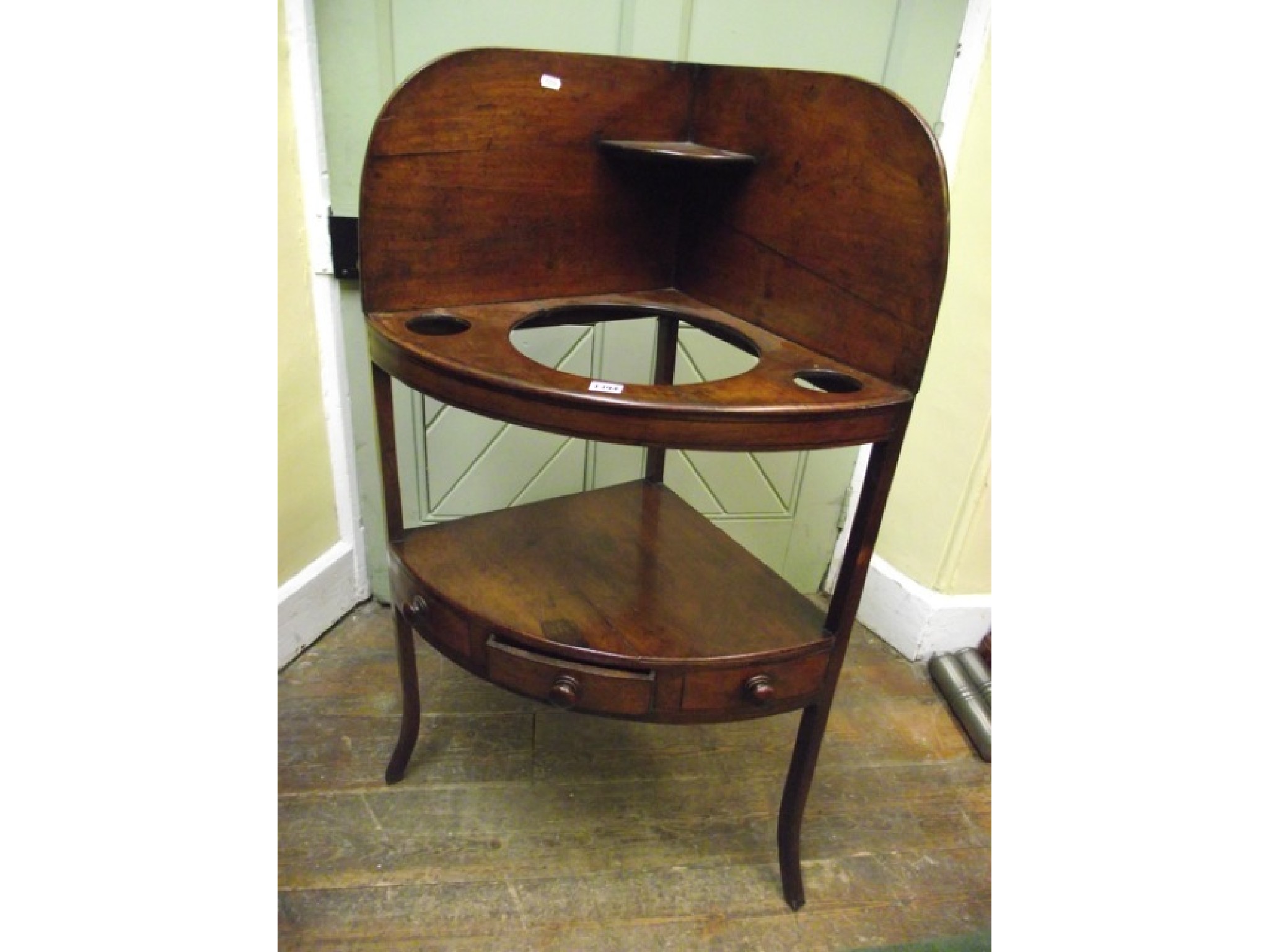 Appraisal: A Georgian mahogany corner washstand with raised splashback raised on