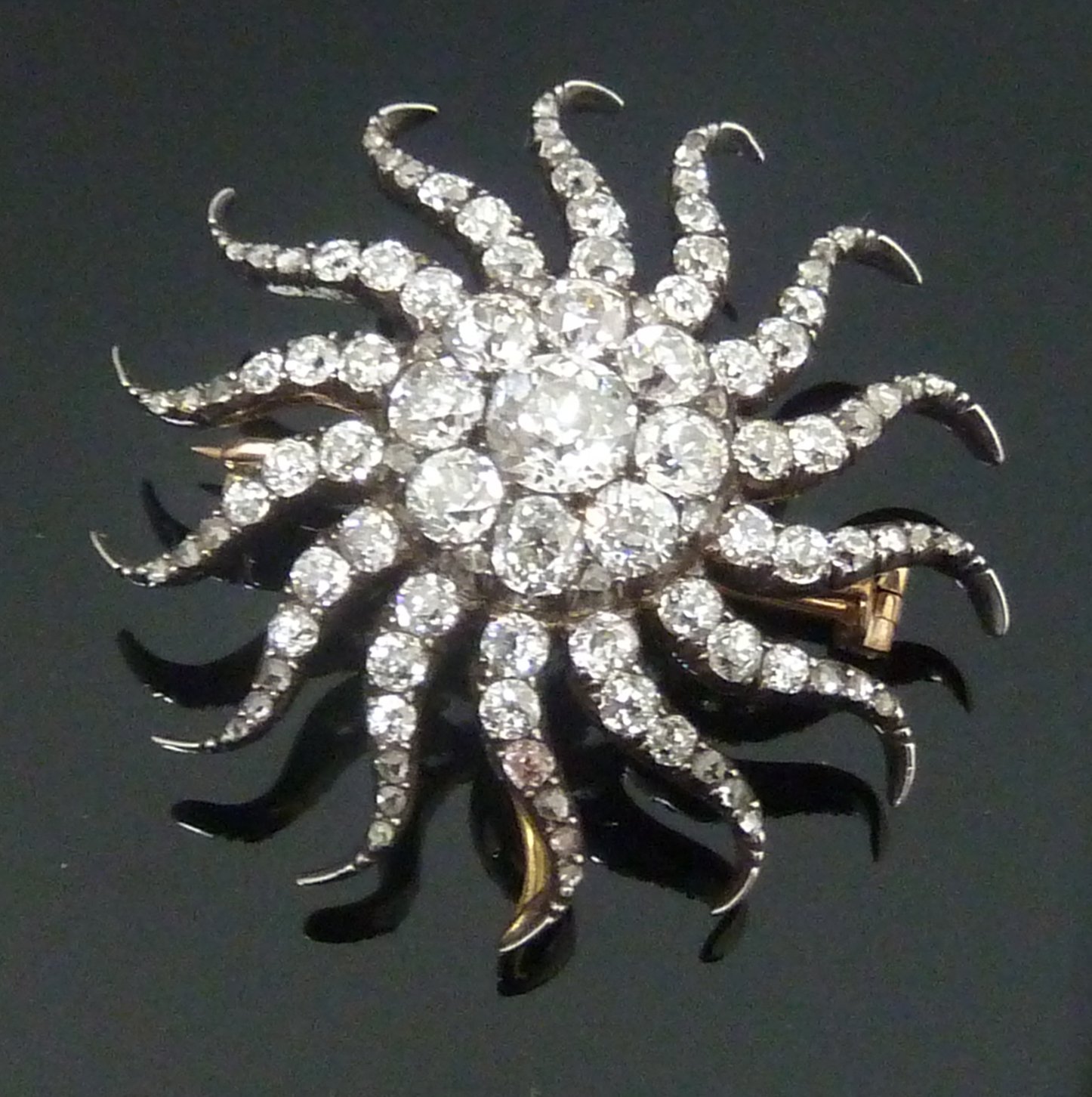 Appraisal: A diamond sunburst brooch pendant centred by a cluster of