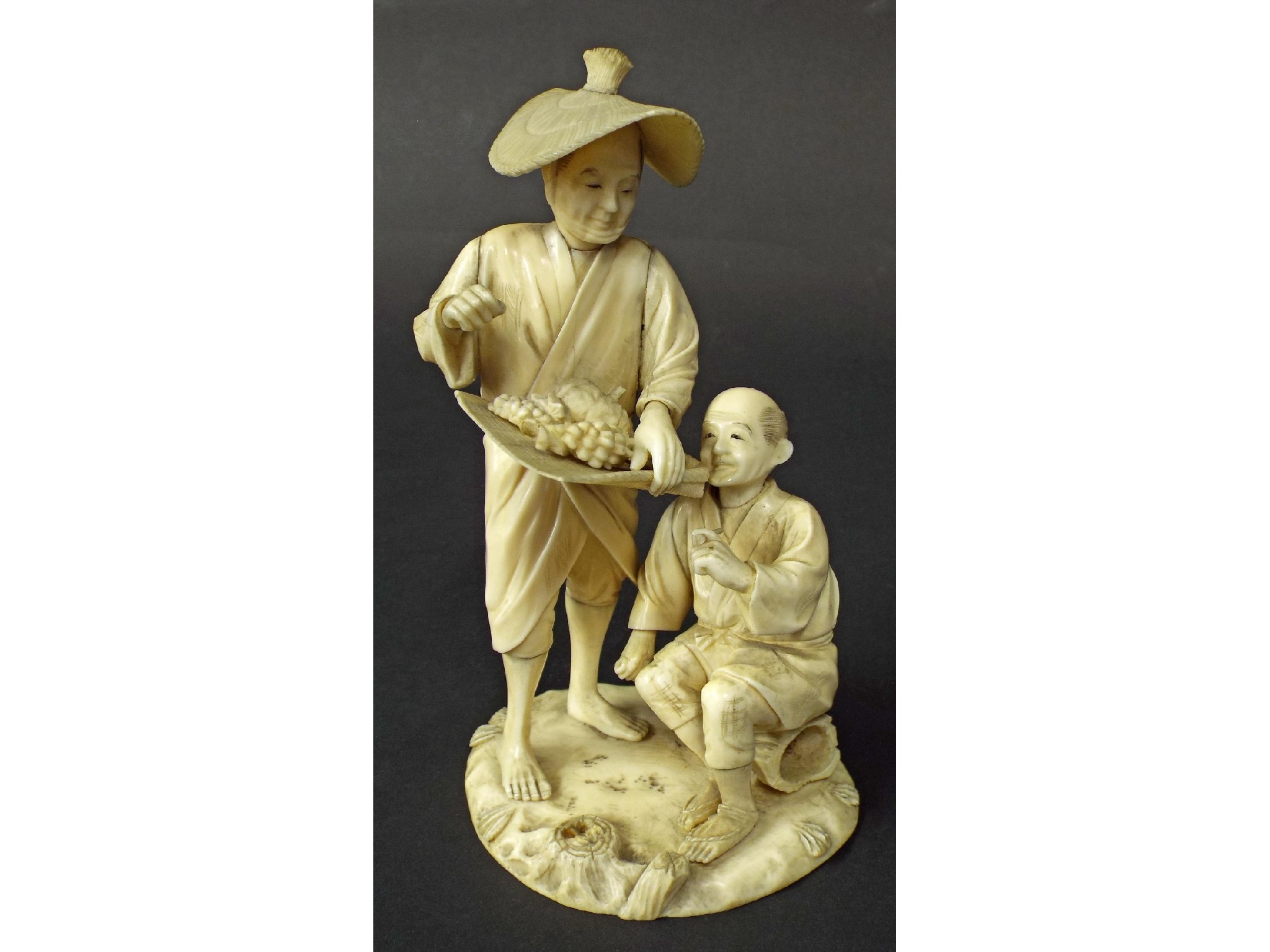 Appraisal: Japanese School carved ivory okimono of a street fruit vendor