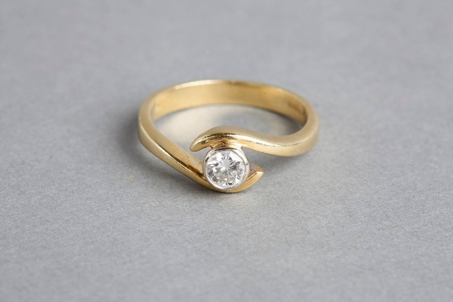 Appraisal: A SOLITAIRE DIAMOND CROSS RING brilliant cut diamond mounted in