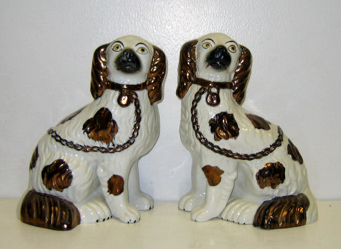 Appraisal: PAIR OF STAFFORDSHIRE POTTERY SEATED SPANIELS Enhanced with copper luster