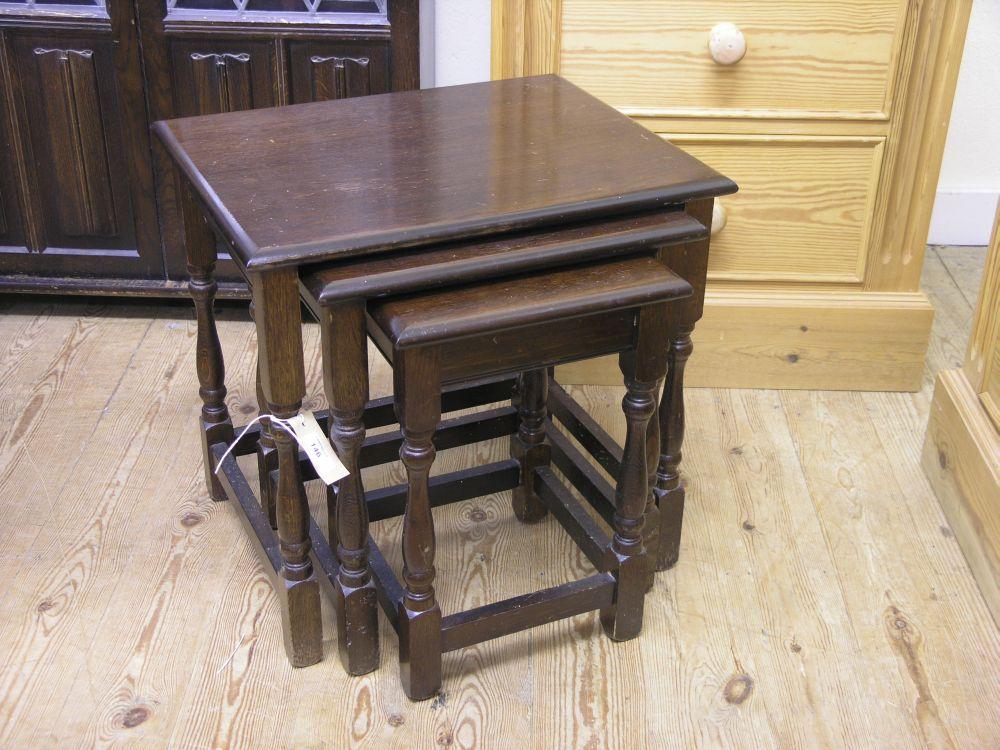 Appraisal: A dark oak nest of three tables on baluster turned