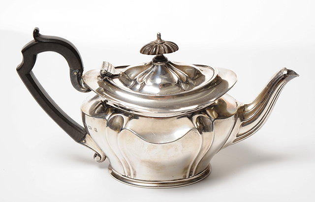 Appraisal: AN EDWARDIAN SILVER TEAPOT OF OVAL SERPENTINE OUTLINE with scroll