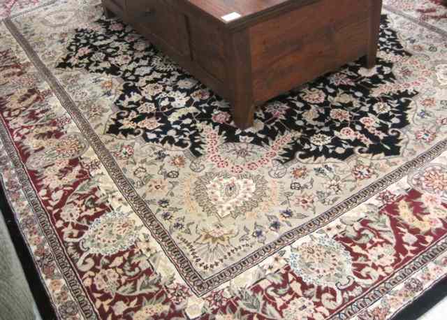 Appraisal: HAND TUFTED ORIENTAL CARPET Indo-Persian floral and central floral medallion