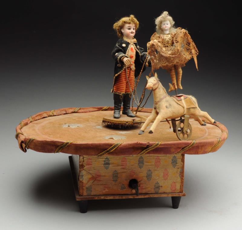 Appraisal: Musical Mechanical Circus Toy Bisque-headed ringmaster guides an acrobat lady