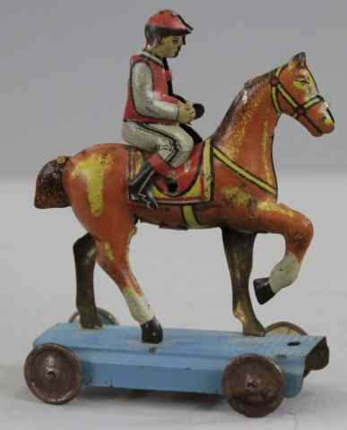 Appraisal: JOCKEY ON HORSE PENNY TOY Germany lithographed tin jockey seated