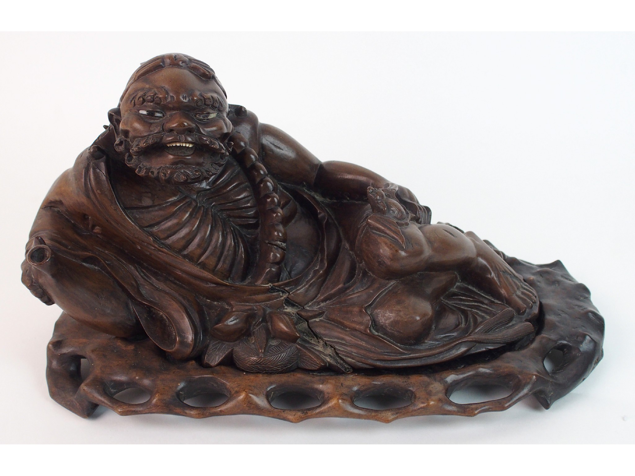 Appraisal: A Chinese hardwood carving of an emaciated figurelying and holding