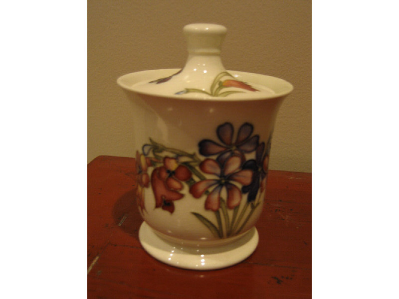 Appraisal: MOORCROFT ENGLAND White glazed pottery lidded jar decorated with a