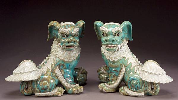 Appraisal: A pair of glazed pottery lions Each pup half-seated and