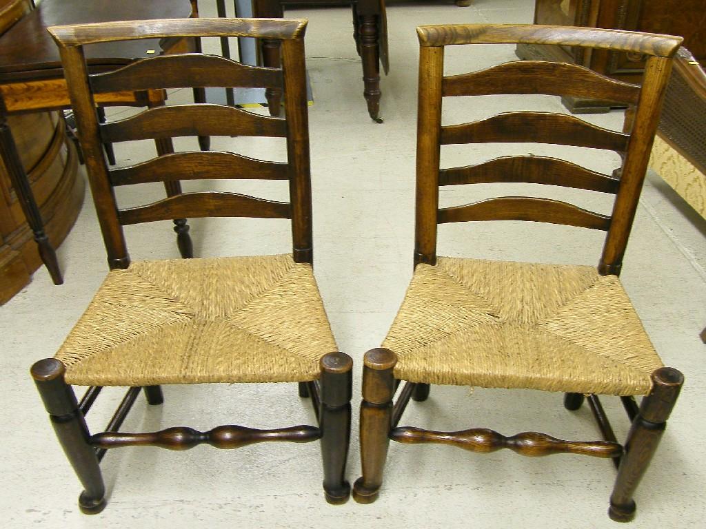 Appraisal: Pair of th century country elm ladderback chairs with rush